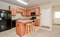 kitchen with black fridge, a kitchen breakfast bar, a center island, and stove