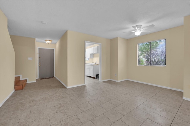 empty room with sink, light tile patterned floors, and ceiling fan