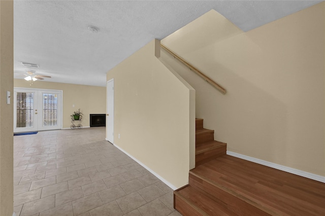 staircase featuring french doors, ceiling fan, tile patterned floors, and a textured ceiling