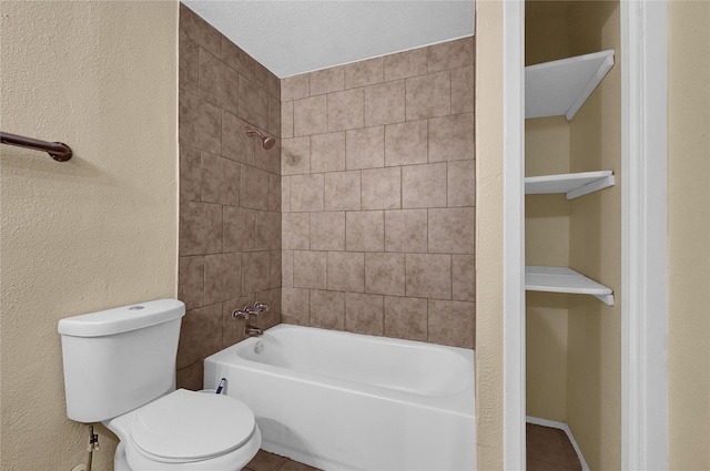 bathroom with toilet, tiled shower / bath combo, and tile patterned flooring