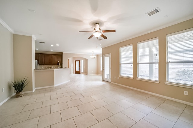 unfurnished living room featuring light tile patterned flooring, ornamental molding, and ceiling fan with notable chandelier