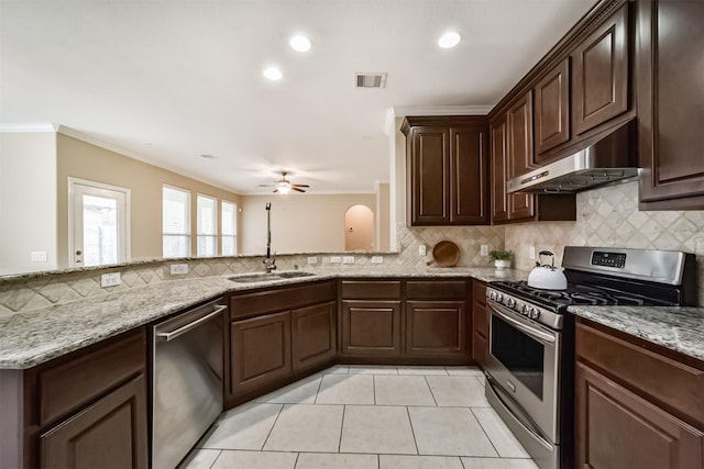 kitchen with stainless steel appliances, tasteful backsplash, ornamental molding, and light stone counters