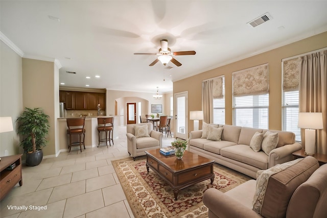 tiled living room with crown molding, plenty of natural light, and ceiling fan with notable chandelier