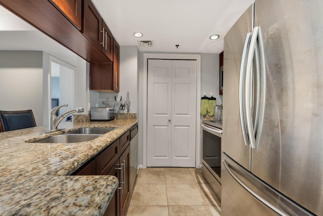 kitchen featuring light stone counters, sink, light tile patterned floors, and appliances with stainless steel finishes