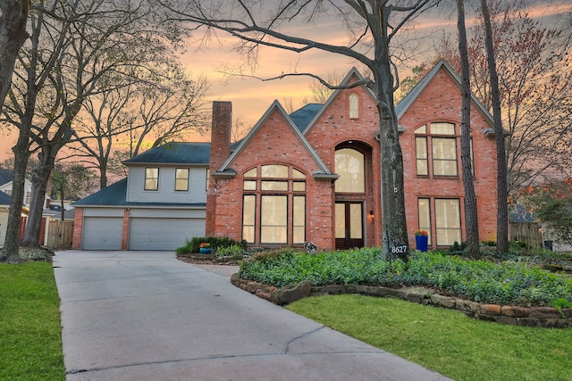 view of front of property featuring driveway, a garage, a chimney, and brick siding