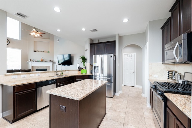 kitchen featuring sink, kitchen peninsula, ceiling fan, stainless steel appliances, and light stone countertops