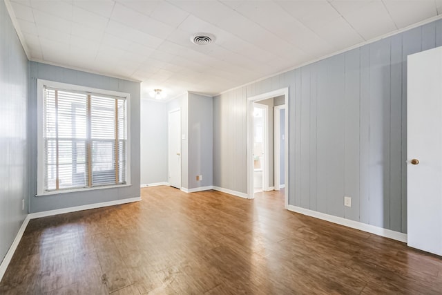 empty room featuring crown molding and wood-type flooring