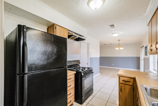 kitchen featuring hanging light fixtures, butcher block counters, light tile patterned floors, and black appliances