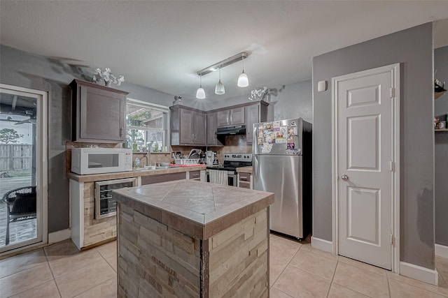 kitchen with wine cooler, sink, a kitchen island, pendant lighting, and stainless steel appliances