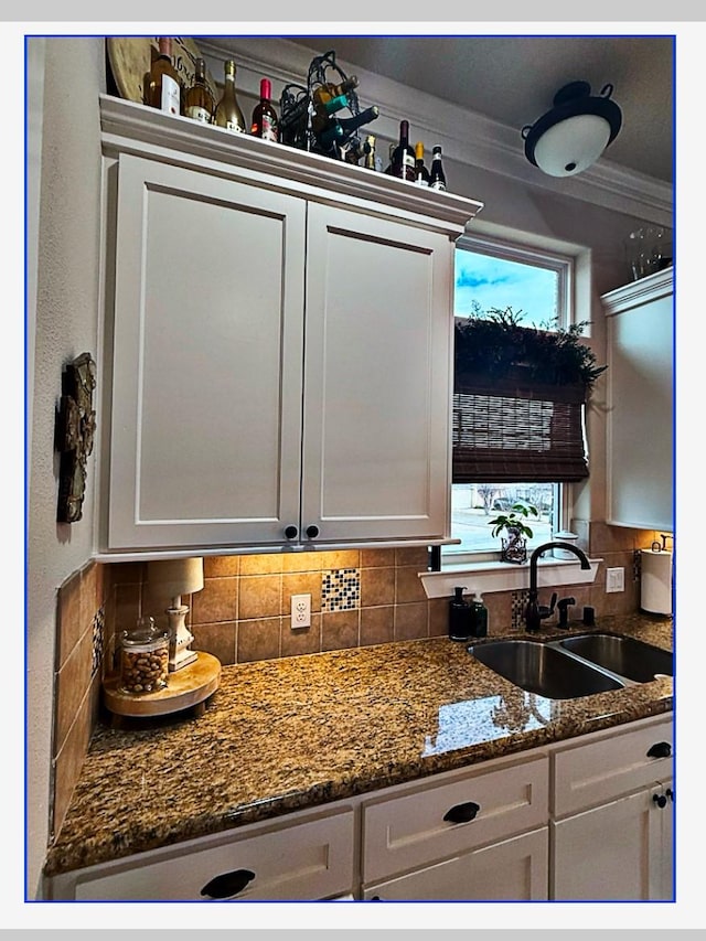 kitchen featuring tasteful backsplash, white cabinetry, sink, and ornamental molding