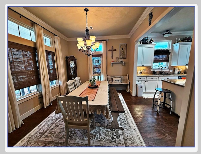 dining area with ornamental molding, dark wood-type flooring, sink, and a chandelier