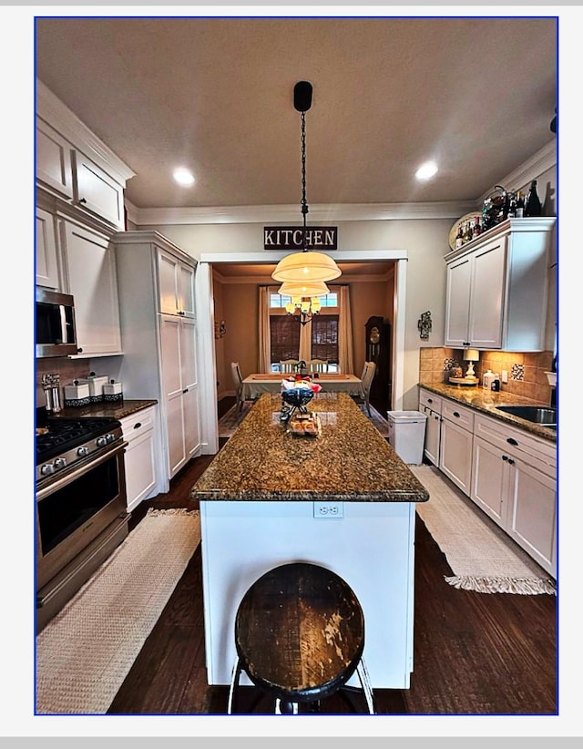 kitchen with sink, decorative light fixtures, dark hardwood / wood-style flooring, stainless steel appliances, and backsplash