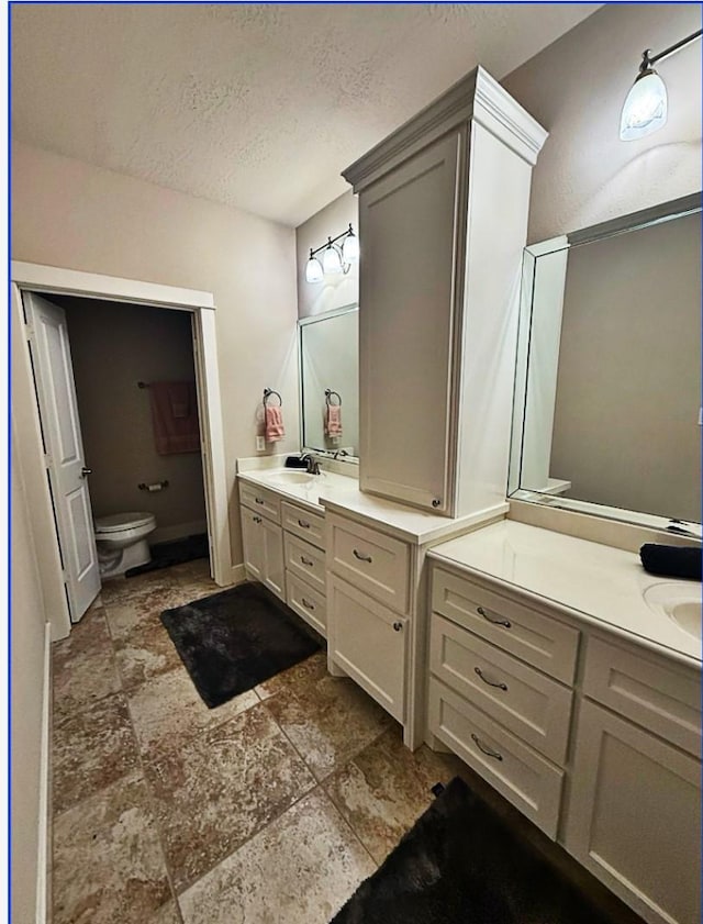 bathroom with vanity, toilet, and a textured ceiling