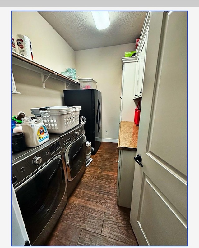 laundry area featuring cabinets, dark hardwood / wood-style floors, a textured ceiling, and washer and clothes dryer