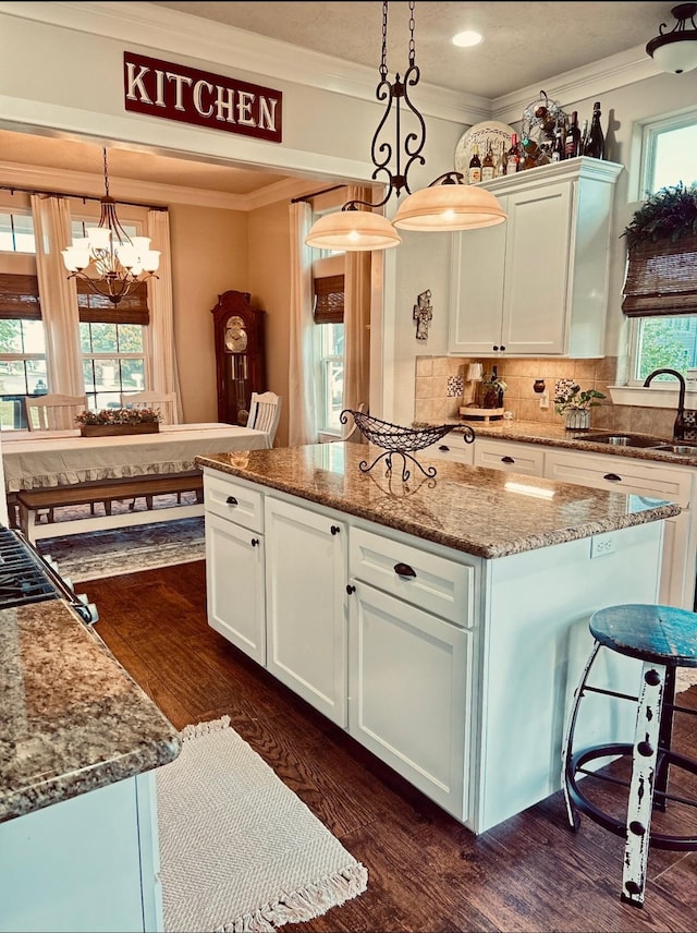 kitchen with dark wood-type flooring, plenty of natural light, a center island, and a sink