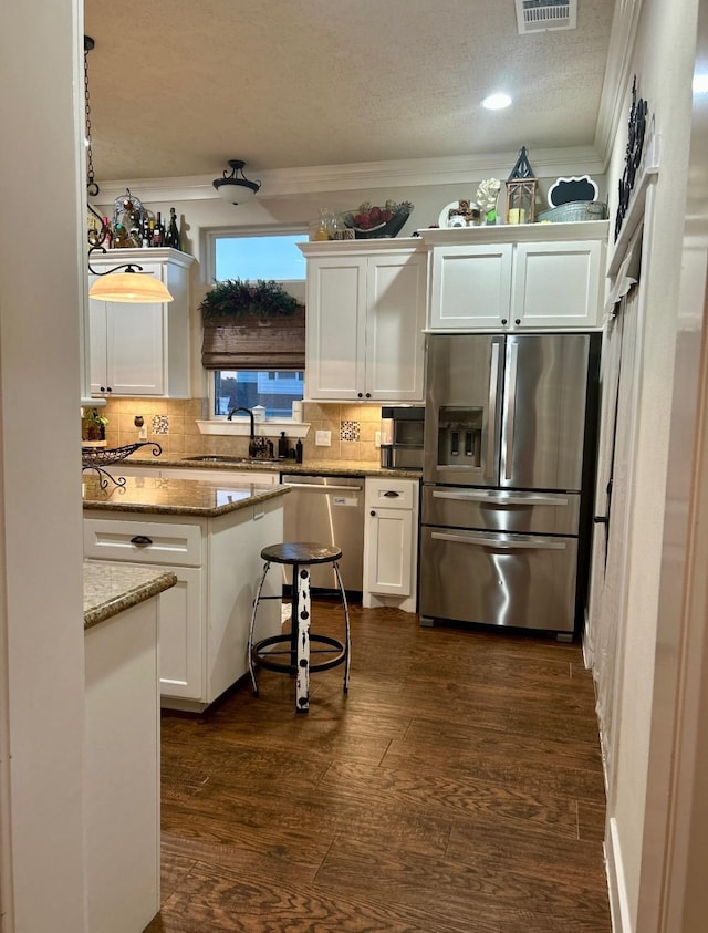 kitchen with white cabinets, appliances with stainless steel finishes, ornamental molding, and a sink