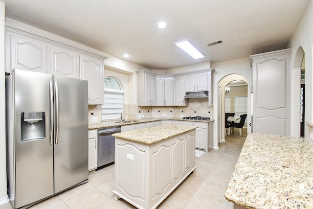 kitchen featuring sink, appliances with stainless steel finishes, white cabinetry, a center island, and tasteful backsplash