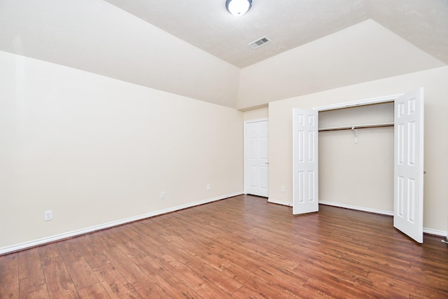 unfurnished bedroom featuring lofted ceiling, a closet, and dark hardwood / wood-style floors