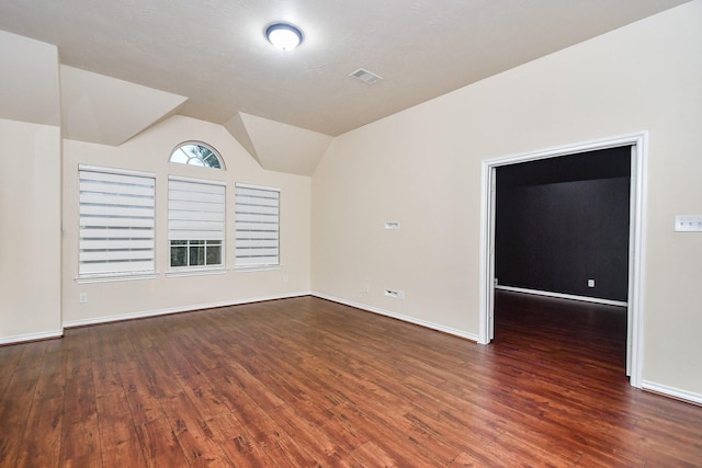 empty room with dark hardwood / wood-style flooring and vaulted ceiling