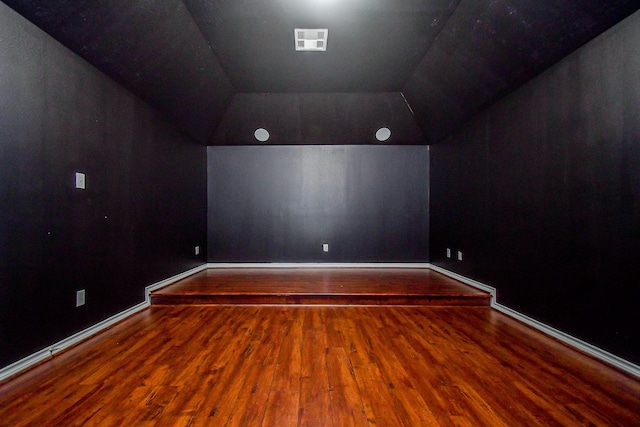 cinema room with vaulted ceiling and hardwood / wood-style floors