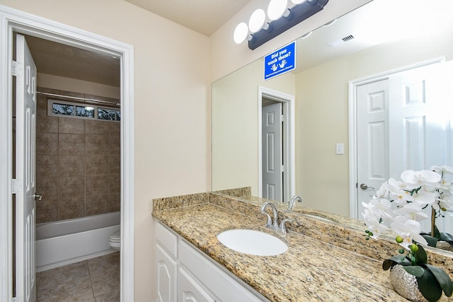 full bathroom with tile patterned flooring, vanity, tiled shower / bath, and toilet