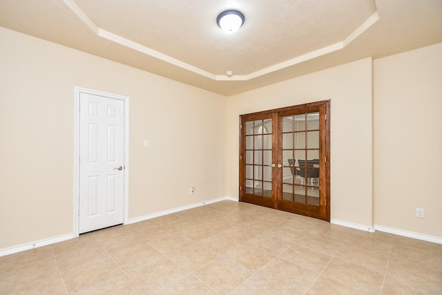 tiled spare room with a raised ceiling, a textured ceiling, and french doors