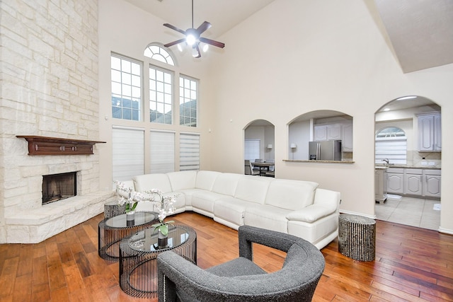 living room featuring hardwood / wood-style floors, a stone fireplace, high vaulted ceiling, and sink