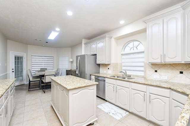 kitchen with white cabinetry, appliances with stainless steel finishes, sink, and light stone counters