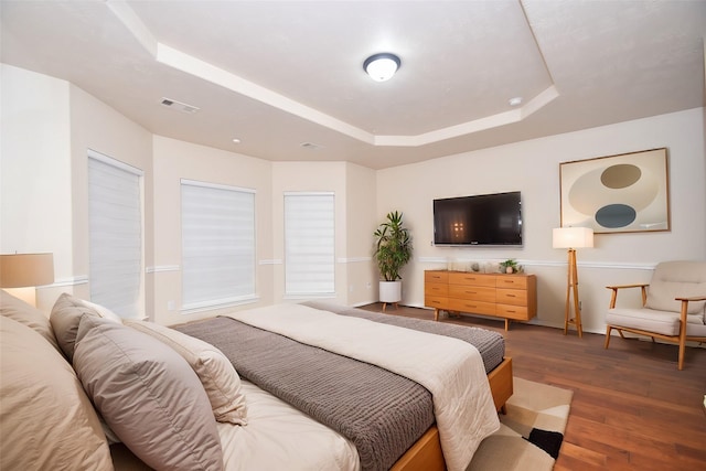 bedroom featuring dark hardwood / wood-style flooring and a raised ceiling