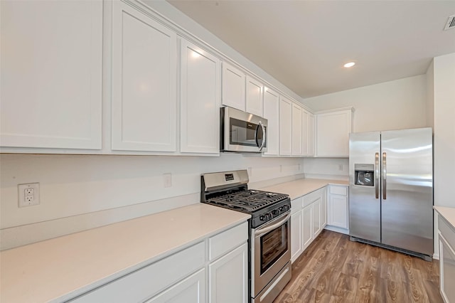 kitchen featuring stainless steel appliances, white cabinets, and light hardwood / wood-style flooring