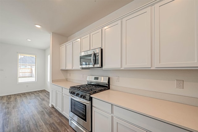 kitchen with appliances with stainless steel finishes, dark hardwood / wood-style floors, and white cabinets