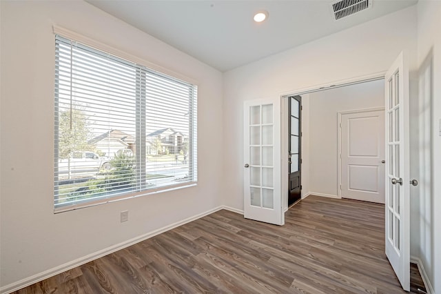 spare room with french doors, dark hardwood / wood-style floors, and a wealth of natural light