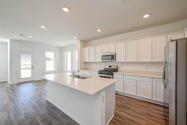 kitchen with sink, a kitchen island with sink, stainless steel appliances, white cabinets, and dark hardwood / wood-style flooring