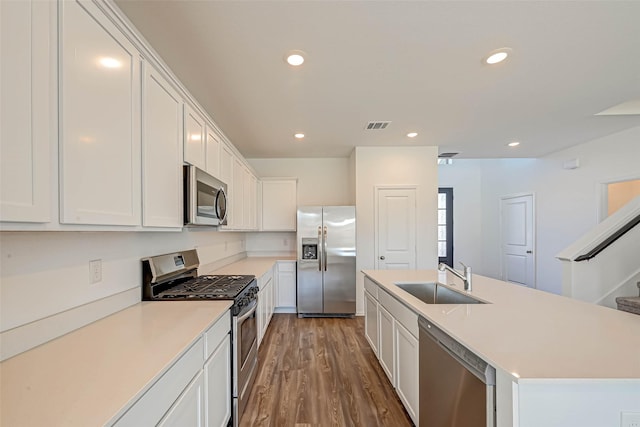 kitchen with sink, white cabinetry, appliances with stainless steel finishes, an island with sink, and hardwood / wood-style floors