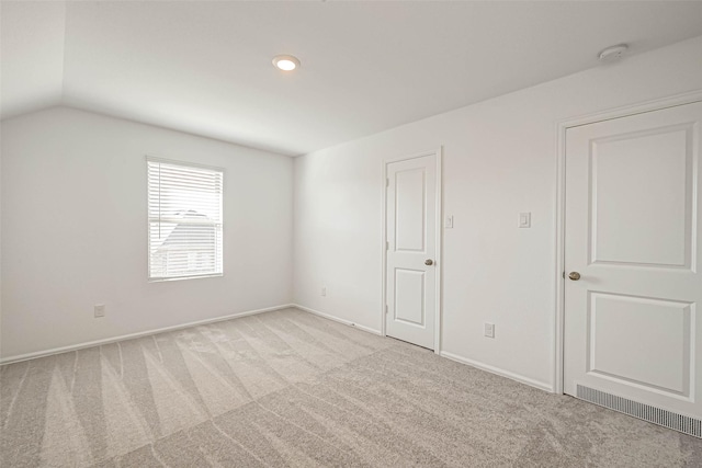 unfurnished room with light colored carpet and vaulted ceiling