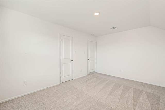 spare room with vaulted ceiling and light colored carpet