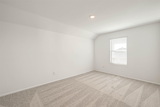 carpeted empty room featuring vaulted ceiling