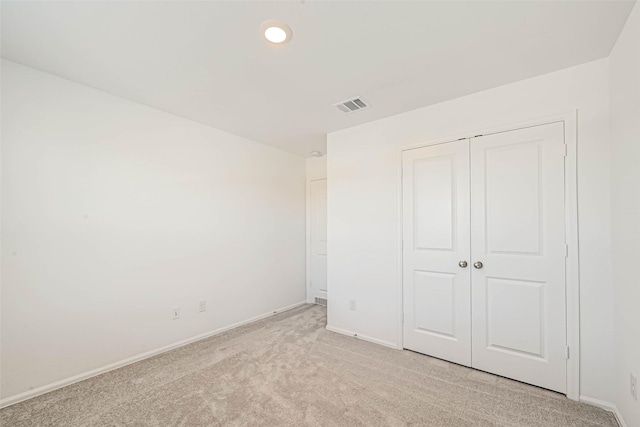 unfurnished bedroom with light carpet and a closet