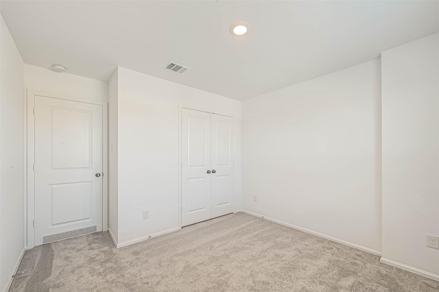 unfurnished bedroom with light carpet and a closet