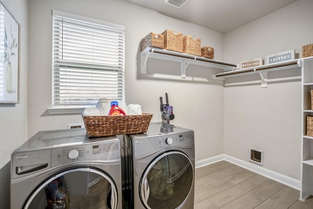 laundry area with independent washer and dryer and light hardwood / wood-style flooring