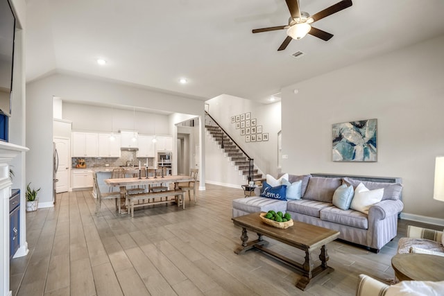 living room featuring vaulted ceiling, light hardwood / wood-style floors, and ceiling fan