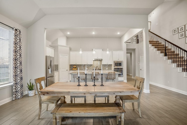 dining area featuring a healthy amount of sunlight, high vaulted ceiling, and light wood-type flooring