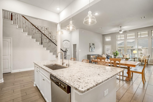 kitchen with sink, white cabinetry, decorative light fixtures, dishwasher, and light stone countertops