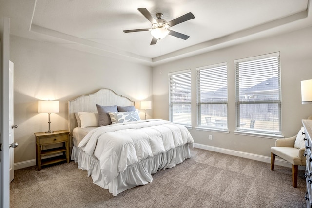 bedroom featuring a tray ceiling, light colored carpet, and ceiling fan