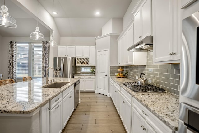 kitchen with sink, a center island with sink, hanging light fixtures, appliances with stainless steel finishes, and white cabinets