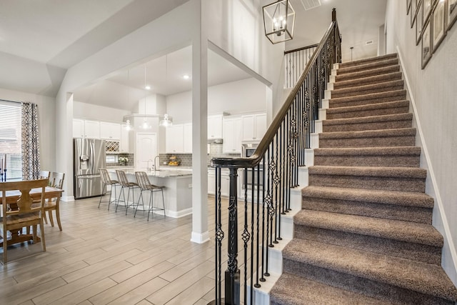 staircase with a high ceiling, hardwood / wood-style floors, and a notable chandelier