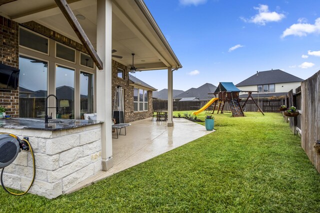 view of yard featuring a playground, a patio, and an outdoor wet bar