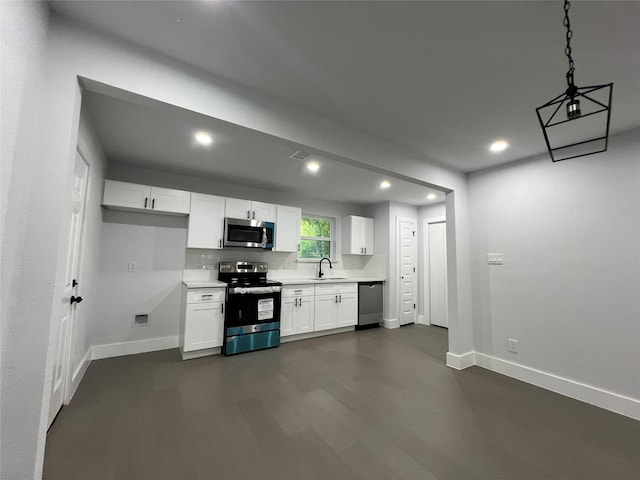 kitchen with appliances with stainless steel finishes, decorative light fixtures, white cabinetry, sink, and dark wood-type flooring