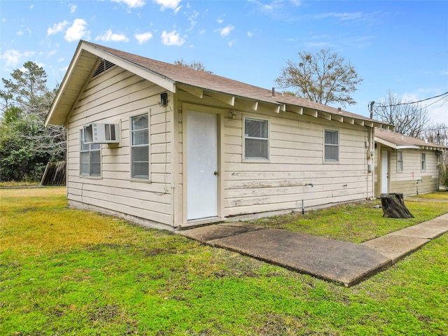 view of property exterior with a wall unit AC and a lawn