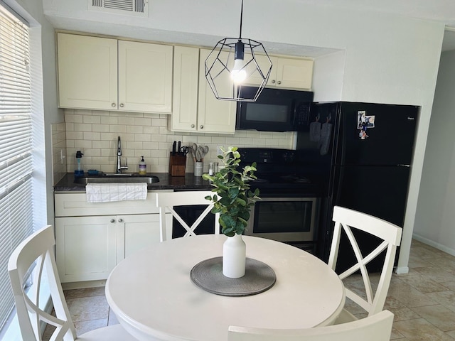 kitchen with pendant lighting, backsplash, sink, and black appliances